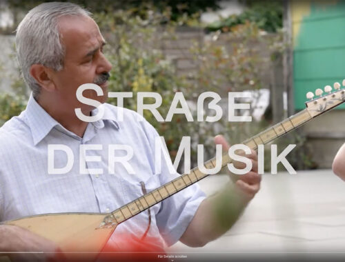 Videovorschaubild für die Straße der Musik. Ein Mann mit einem gitarrenähnlichen Instrument spielt Musik im Freien.
