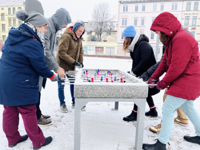 Angestellte der Projektmeisterei Lehe spielen im Schnee auf dem Leher Pausenhof mit dem Tischkicker.