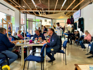 Veranstaltung „Repair fair - Reparieren und Aufmöbeln“ in der wunderwerft. 13 Personen, die an Tischen sitzen oder stehen reparieren unterschiedliche Dinge und unterhalten sich dabei.