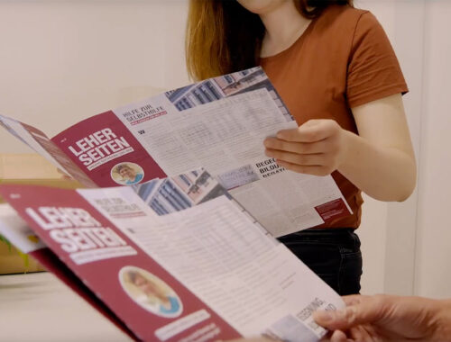Zwei Personen schauen sich jeweils eine Ausgabe der Leher Seiten an.