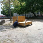 Pflanzmöbel auf dem Leher Pausenhof. Im Vordergrund hockt ein Junge vor der Sitzgelegenheit aus Holz.