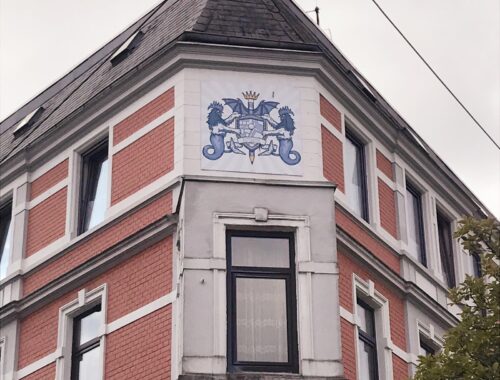 Das Wappen von Bremerhaven Lehe ist oben an einer Hauswand in Lehe über einem Fenster sichtbar.