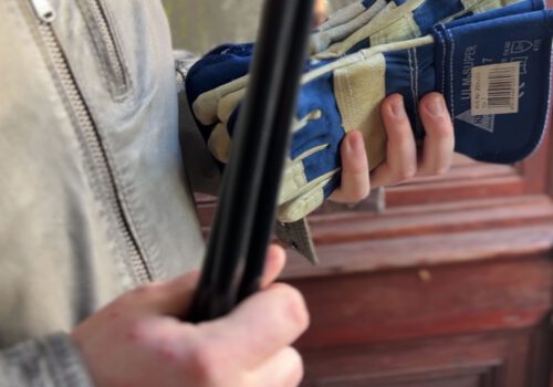 Hände halten einen Müllgreifer und Handschuhe