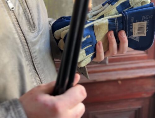 Hände halten einen Müllgreifer und Handschuhe