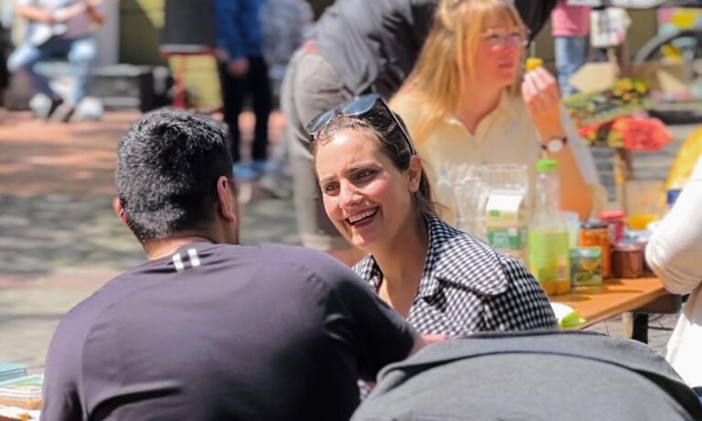 Menschen unterhalten sich und essen zusammen beim Straßenpicknick in Bremerhaven Lehe.