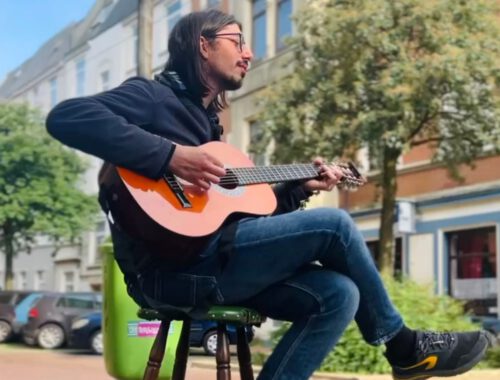 Eine Person sitzt auf einem Barhocker und spielt Gitarre