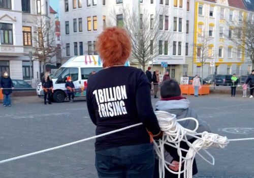 DIe Rücken von zwei Personen. Ein kleiner Junge steht neben einer Frau die ein 