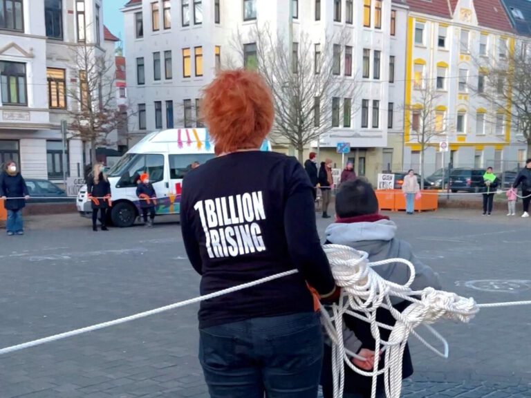 DIe Rücken von zwei Personen. Ein kleiner Junge steht neben einer Frau die ein 