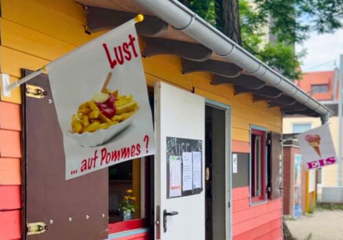 Ein buntes Holzhaus mit Werbung für Pommes und Eis