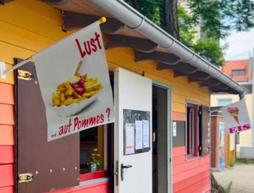 Ein buntes Holzhaus mit Werbung für Pommes und Eis