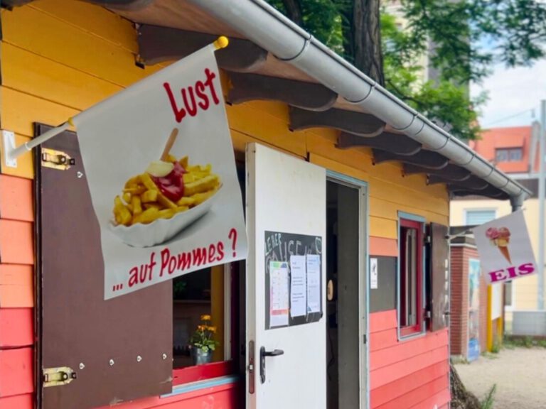 Ein buntes Holzhaus mit Werbung für Pommes und Eis