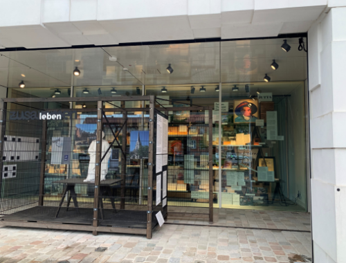 Blick auf Glasfront, die sich in einer Hausöffnung befindet. Dahinter sind verschiedene Ausstellungsexponate zu sehen.