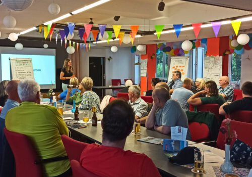 Viele Menschen sitzen an Tischen als Gäste bei der Stadtteilkonferenz