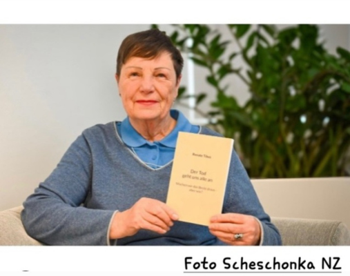 Porträtfoto einer älteren Frau mit kurzen braunen Haaren, die ihr Buch 
