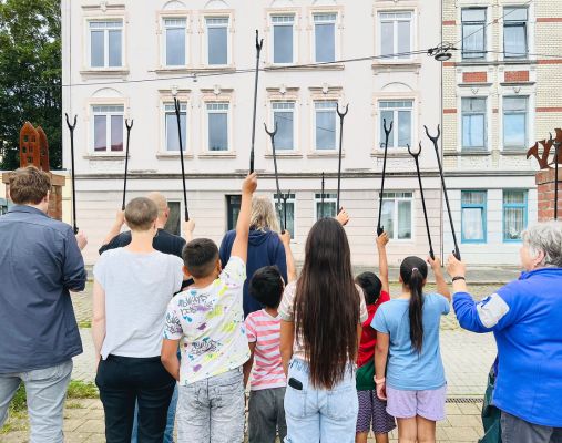 Kinder mit Müllzangen vor einem Haus