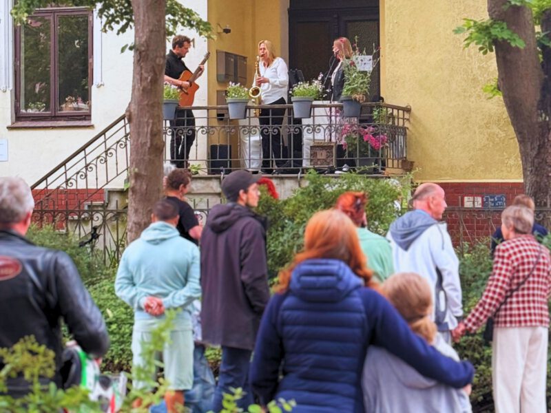 viele Menschen stehen auf der Straße und lauschen Musiker:innen