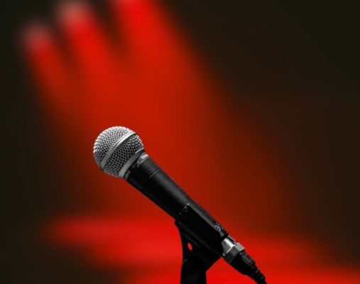 Mikrofon Bühne Ein Mikrofon vor roten Scheinweifern