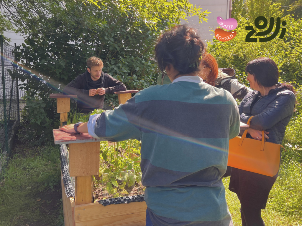 Vier Personen stehen um ein Hochbeet herum