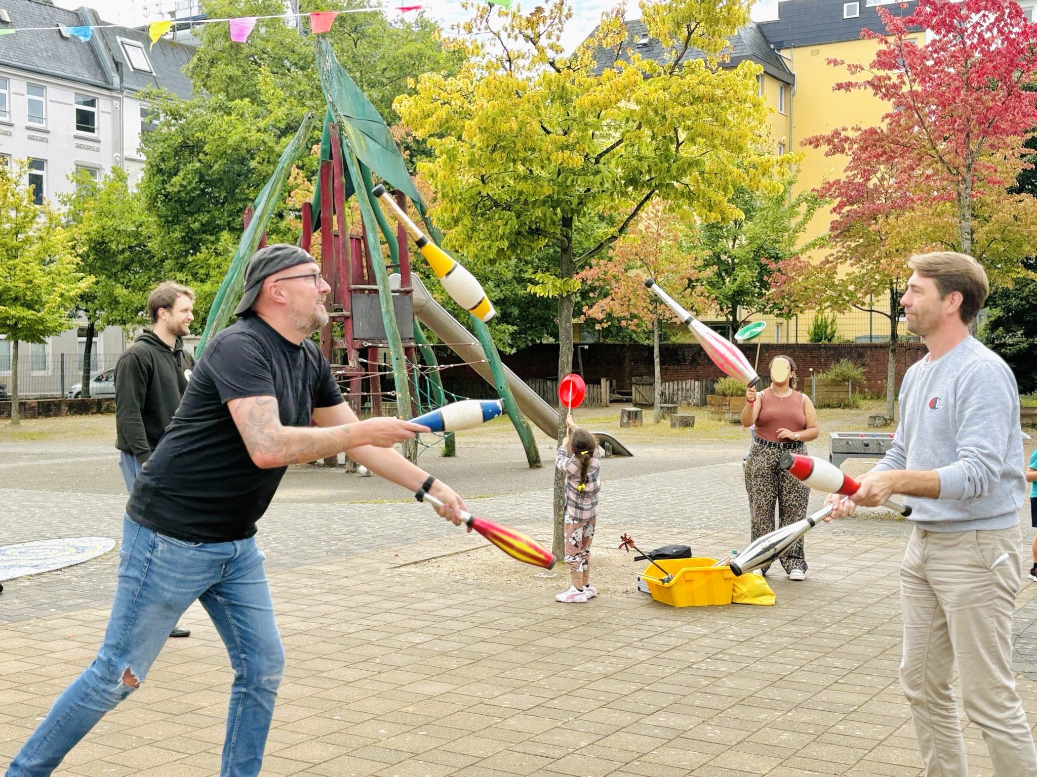 zwei erwachsene Männer jonglieren zusammen mit Keulen