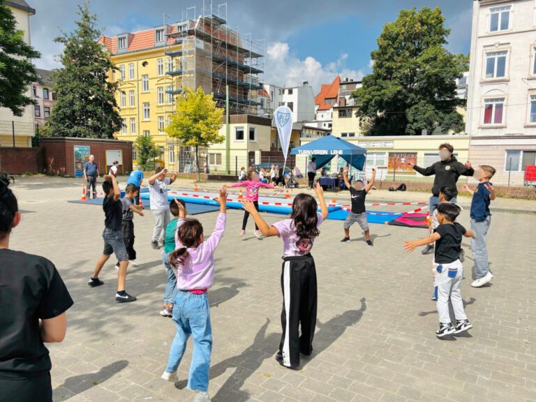 Kinder stehen in einem Kreis und machen gemeinsam Aufwärmübungen für den Urban Sports Day