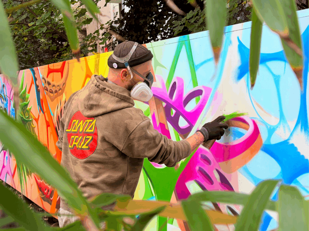 eine Person mit Gasmaske sprüht ein buntes Graffiti