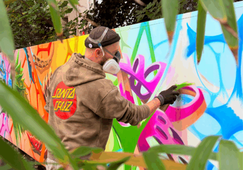 eine Person mit Gasmaske sprüht ein buntes Graffiti