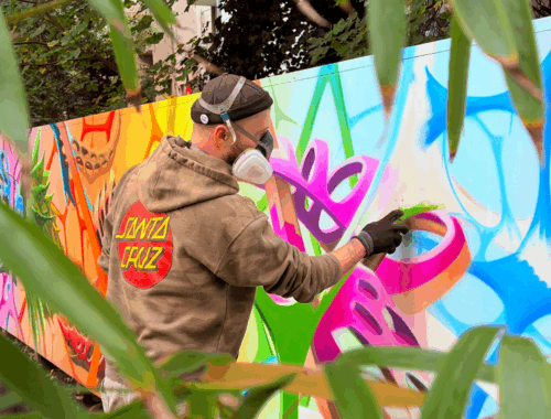 eine Person mit Gasmaske sprüht ein buntes Graffiti