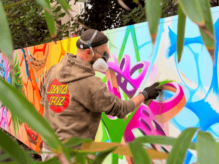 eine Person mit Gasmaske sprüht ein buntes Graffiti