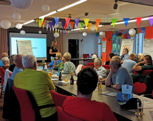 Viele Menschen sitzen an Tischen als Gäste bei der Stadtteilkonferenz