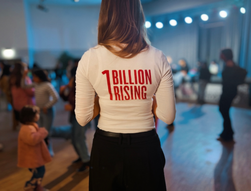 Es ist der Rücken einer Person zu sehen die ein weißes Oberteil trägt auf dem in rot 