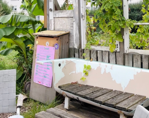 Eine alte Badewanne umgebaut zu einer Bank steht vor einer begrünten Wand im freien