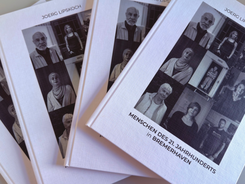 Mehrere Bücher mit Portraitfotos darauf sind übereinander gestapelt