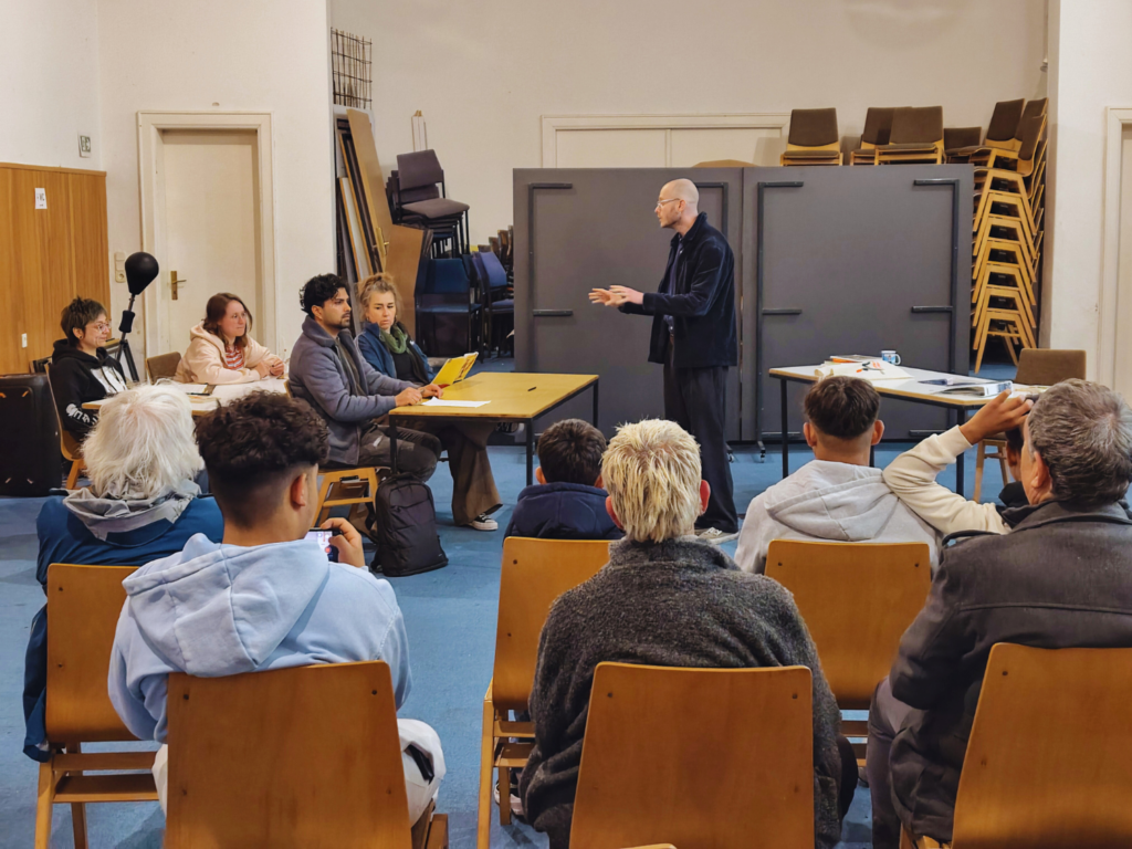 Mehrere Menschen stellen eine Schulunterrichtssituation nach