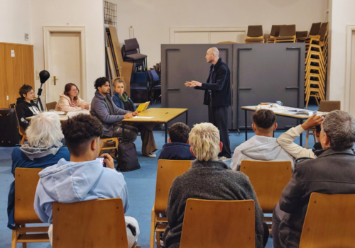 Mehrere Menschen stellen eine Schulunterrichtssituation nach