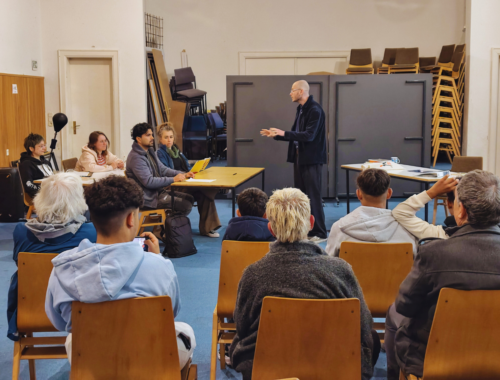 Mehrere Menschen stellen eine Schulunterrichtssituation nach