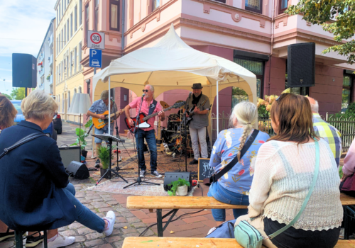 Menschen spielen Musik unter einem kleinen Pavillon auf offener Straße
