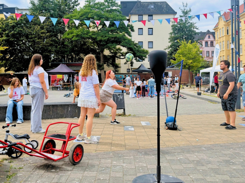 Viele Kinder und Jugendliche stehen auf einem Platz und probieren verschiedene Sportarten aus