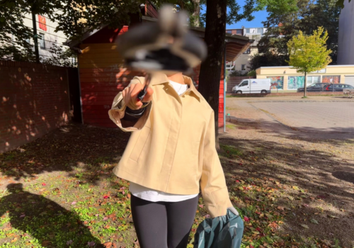Eine Person hält eine Mülltüte in der Hand und einen Greifer vor ihr Gesicht